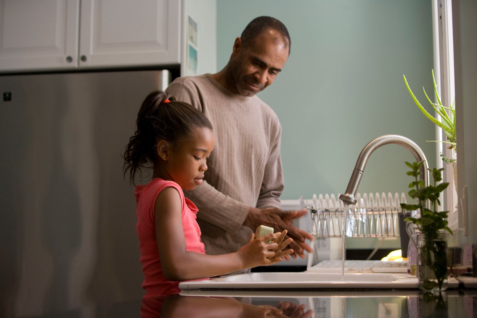 father and daughter washing their hands together.