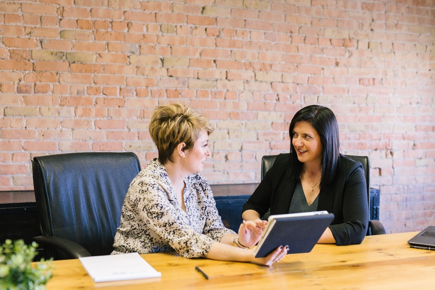Human resource professionals help boost employee engagement. This image shows two women sat together, working and smiling.