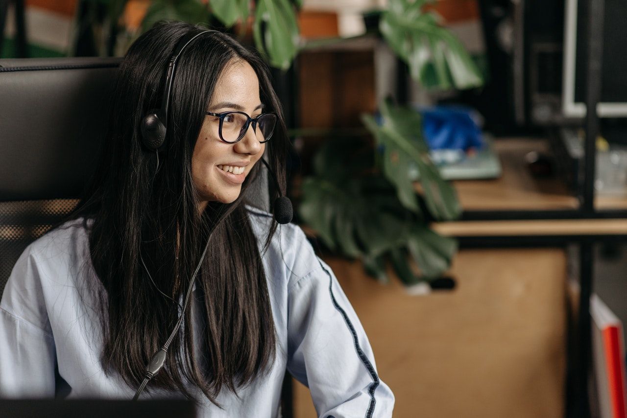 Young woman with a headset on looking away from the camera and smiling.